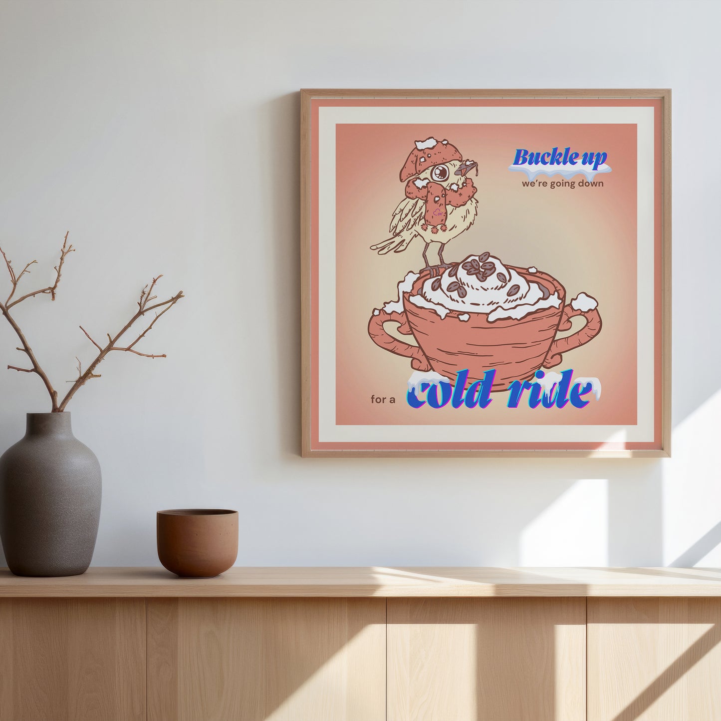 Digital illustration of a small yellow bird wearing a pink scarf and a beanie, on the edge of a fancy coffee mug. The title "Buckle up, we're going down for a cold ride" with emphasis on "buckle up" and "cold ride" is present on the illustration. The overall illustration is on shade of soft pink and yellow.