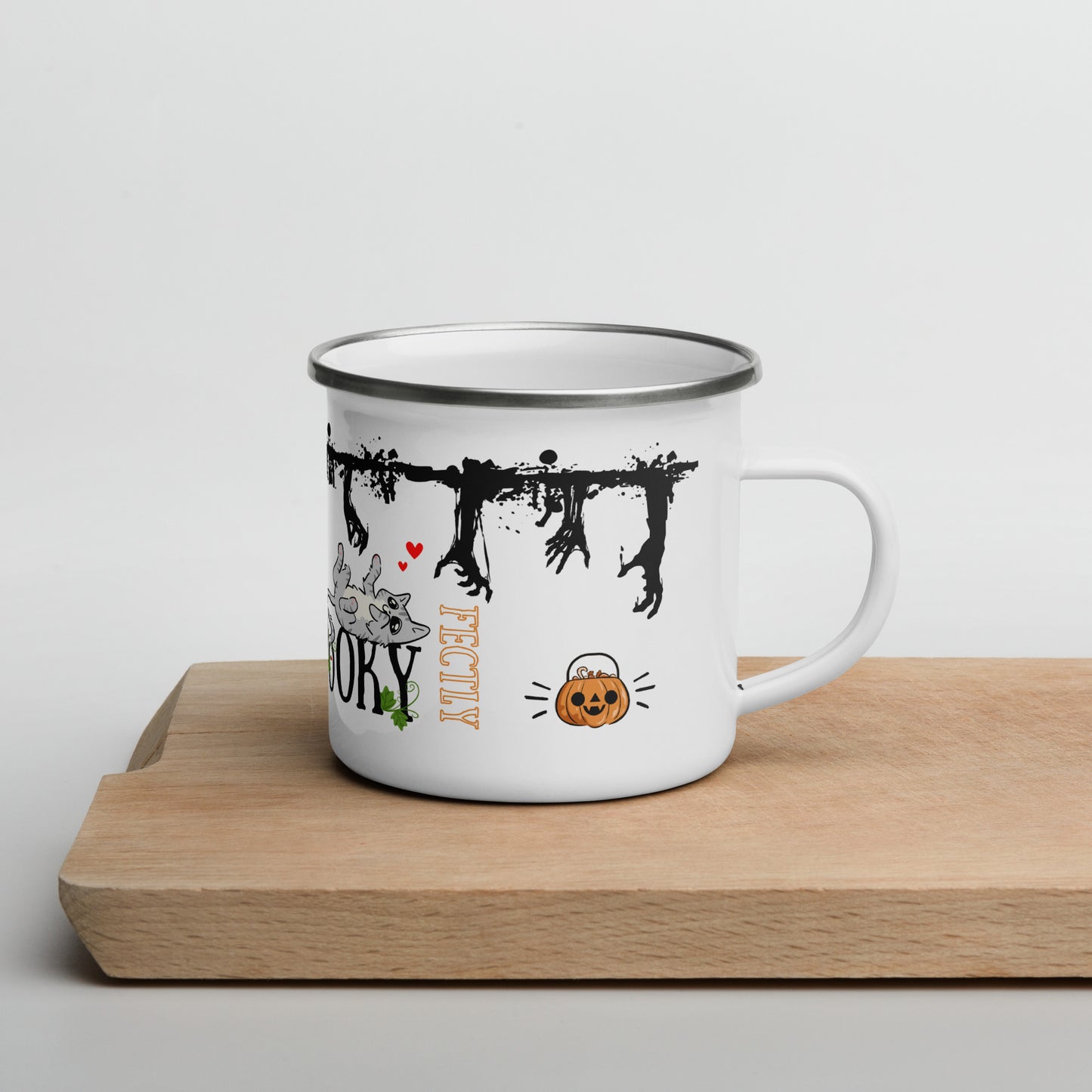 Illustrated enamel mug with zombie hands going through the top of the mug, while cats are playing. The words "Purr-fectly Spooky" are present on the mug, with smily pumpkins and vines.