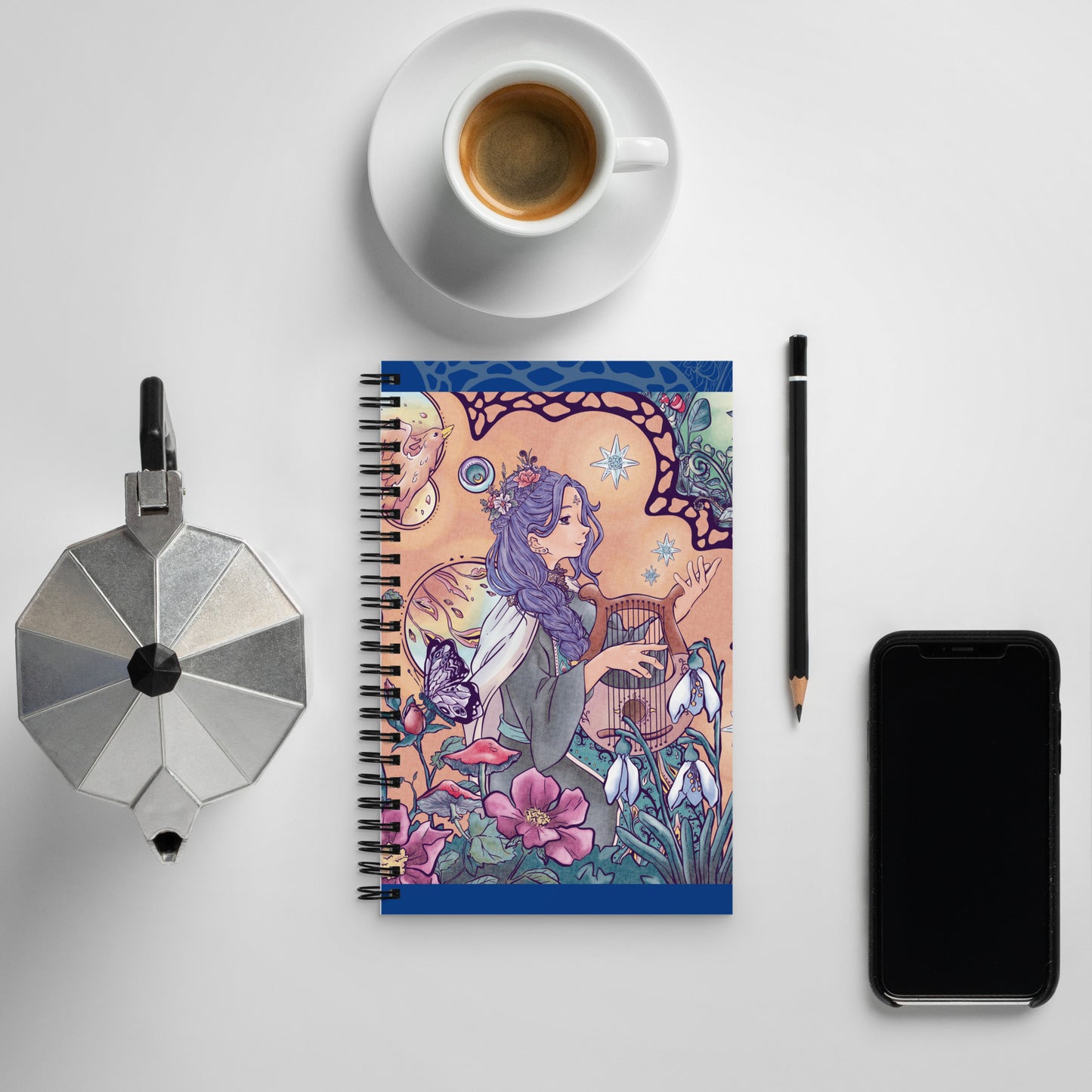 Spiral notebook with the illustration of an enchanted forest, phoenix and singing princess. The drawing is detailed and manga style. The warm color palette of the character brings a soft vibe to the green vegetation.