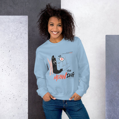 Woman wearing a light blue crew neck sweatshirt with illustration of a cat trying to break into a door. Parody of the Shining, this design is called "The Meowing & scratching" because you never know when he's gonna strike. This version shows a cute cat showing the finger while trying to enter the room.